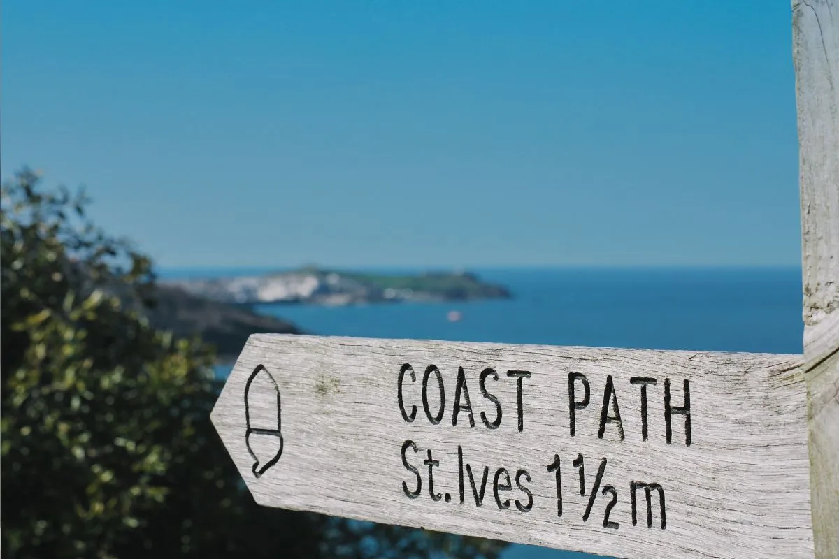 Wegweiser des South West Coast Path über der Küste, im Hintergrund St Ives